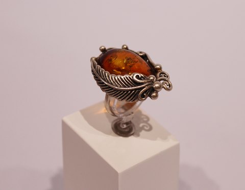 Ring with large piece of amber decorated with feather of 925 sterling silver and 
stamped SAN.
5000m2 showroom.
