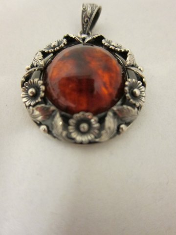 Pendant made of silver with amber
N. E. From,  Danmark
Please note the very beautifully decorated eye to put the chain through (comes 
without a chain)
Stamp: NS From 925 Sterling Denmark
Diam: 3cm
PLEASE NOTE: NO SILVER IN THE SHOWROOM