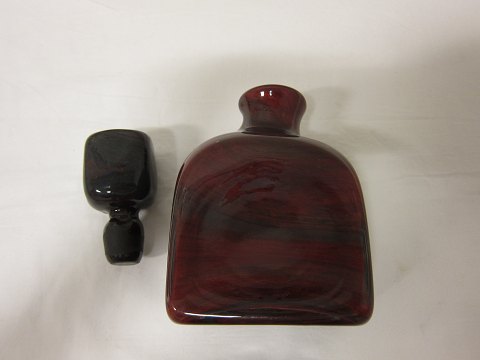 Decanter with the stopper, made by Holmegaard, Denmark
Unica decanter in a voluminous very beautiful blown "dark-amber"cloured glass 
and a red/lilac "flame-coloured" shine
Produced: 1965
Design: Per Lütken
From the Lava-serie, but rare seen as a decan