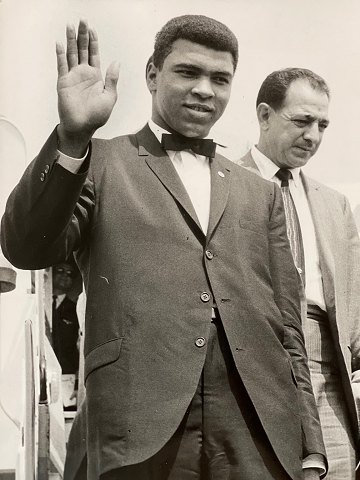 Vintage press photo of the boxer Muhammad Ali / Cassius Clay (1942 - 2016) 
waving on arrival at London Airport for the fight against Henry Cooper in 1966