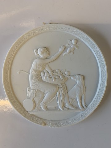 Royal Copenhagen bisquit platte 
"Hyrdinde med en Amorinerede og Har skår
Bertel Thorvaldsen:
Mindre produktionsrevne
Måler 14,5 cm