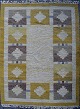 Rölakan tæppe med geometrisk mønster i gule og brune nuancer. 
