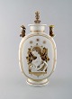 Royal Copenhagen. Lidded art deco jar with the Virgin Mary and the Jesus Child. 
Three praying children with crowns on their heads. Overglaze with gold leaf 
decoration. Rare unique piece in museum quality. Ca. 1920.
