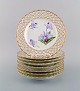 Otte antikke Royal Copenhagen tallerkener i gennembrudt porcelæn med håndmalede 
lilla lotusblomster. Modelnummer 72/1135. Museumskvalitet. Ca. 1910.
