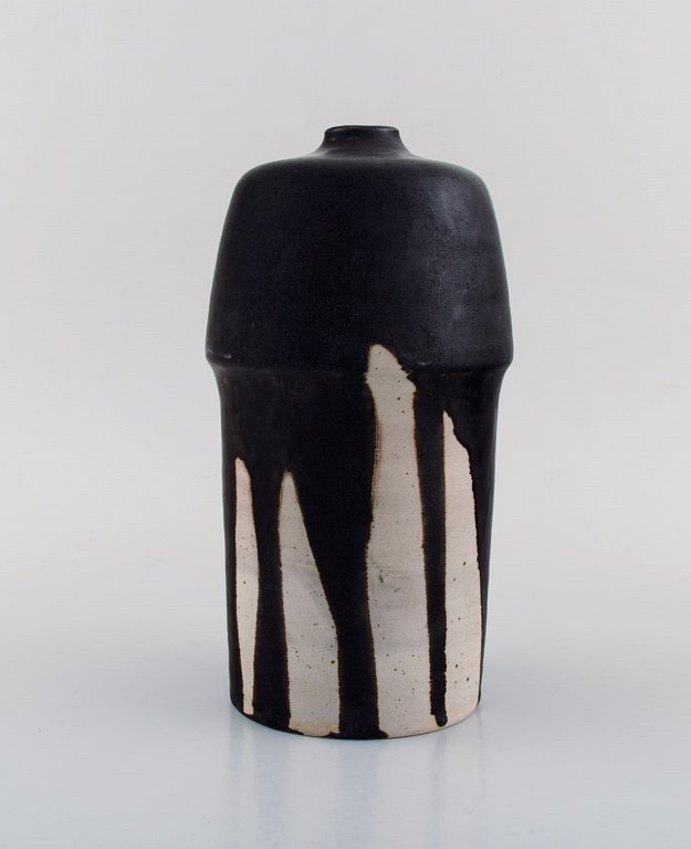 European studio ceramist. Unique vase in glazed ceramics. Black running glaze on 
sand background. 1980