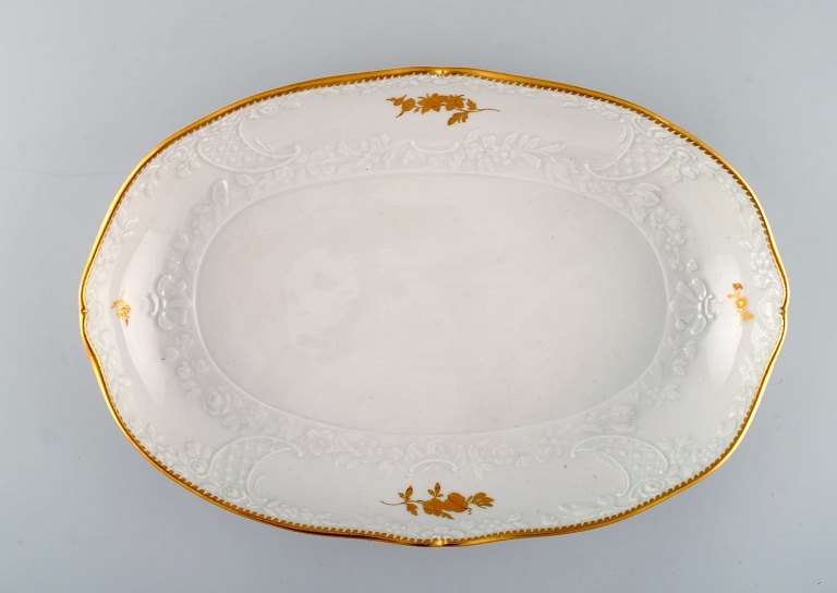 Large Meissen serving dish with flowers and foliage in relief and gold edge. 
20th century. 
