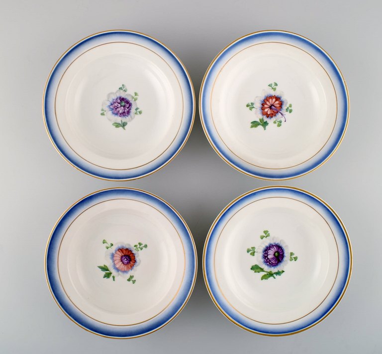 Fire antikke Royal Copenhagen dybe tallerkener i håndmalet porcelæn med blomster 
og blå kant med guld. Modelnummer 592/9050. Sent 1800-tallet. 
