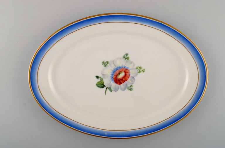 Stort ovalt antikt Royal Copenhagen fad i håndmalet porcelæn med blomster og blå 
kant med guld. Modelnummer 592/9008. Sent 1800-tallet. 

