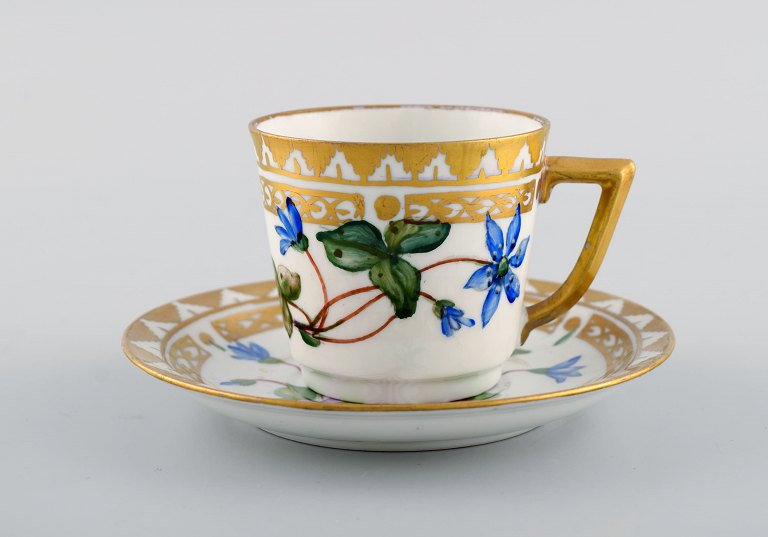 Royal Copenhagen kaffekop med underkop i håndmalet porcelæn med gulddekoration 
og blomster. Flora danica stil, 1960