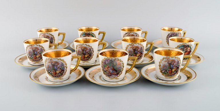 11 Royal Copenhagen kaffekopper med underkopper i porcelæn med romantiske scener 
og gulddekoration. 1900-tallet.
