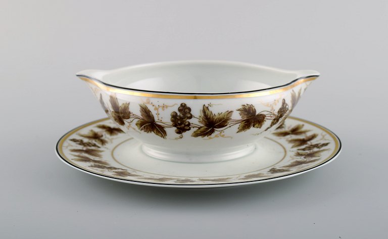 Limoges sauce boat on stand in porcelain with hand-painted grape vines and gold 
decoration. 1930s / 40s.
