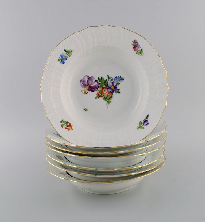 Royal Copenhagen Saksisk Blomst. Syv dybe tallerkener i håndmalet porcelæn med 
blomster og gulddekoration. Modelnummer 493/1615. Tidligt 1900-tallet.
