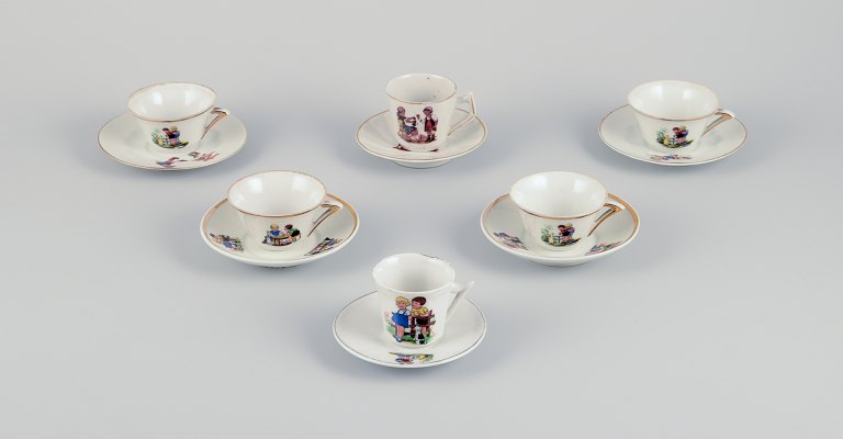 French dolls dinnerware/childrens tea set in porcelain.
Six cups with matching saucers. Gold rim. Motifs of children.
