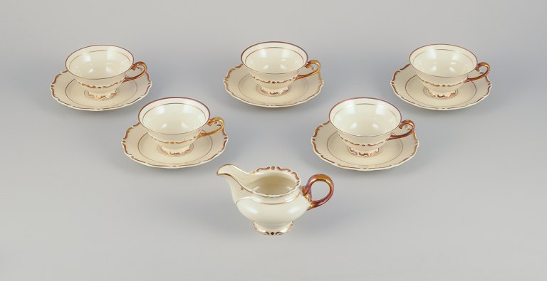 A set of five KP, Karlskrona tea cups with saucers and a creamer in 
cream-colored porcelain with gold decoration.