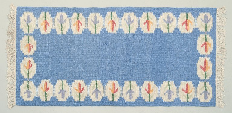 Swedish handwoven carpet in pure wool. Rölakan technique.
Designed with flowers on a blue background.