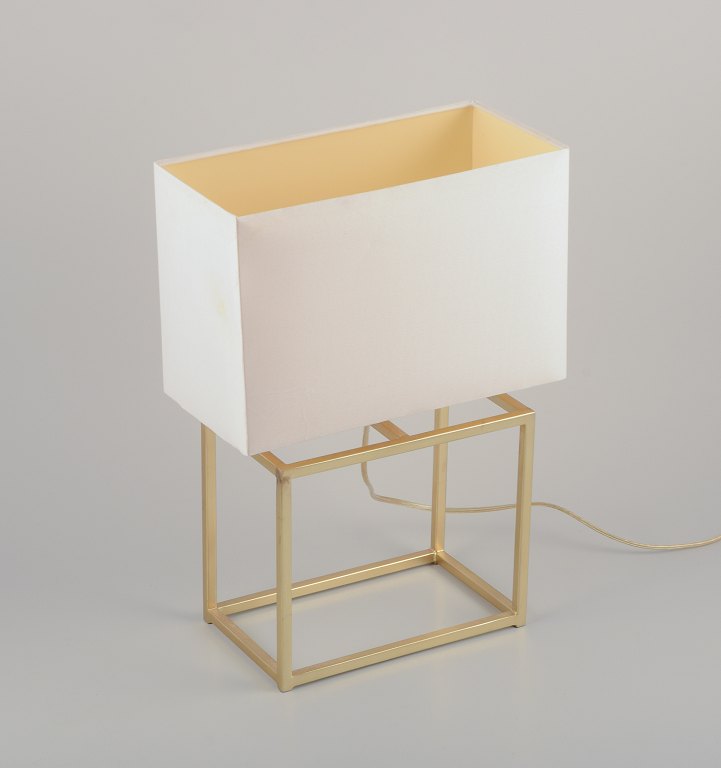 Designer table lamp in brass with a white fabric shade. Modernist and sleek 
design.