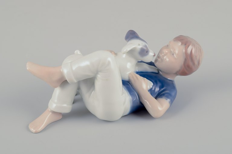 Royal Copenhagen.
Porcelain figurine of a boy with a puppy.